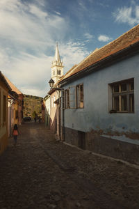 Footpath amidst buildings in city against sky