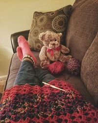 Low section of person relaxing on sofa with toy