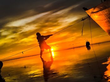 Silhouette man standing by sea against sky during sunset