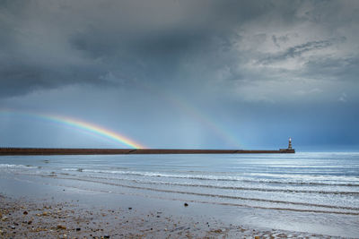 Scenic view of rainbow over sea against sky