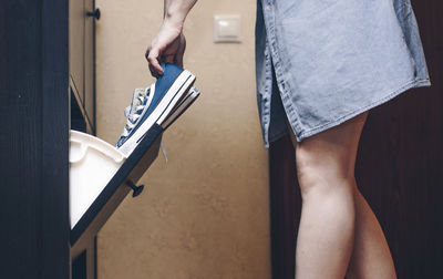 Midsection of woman holding shoes while standing at home