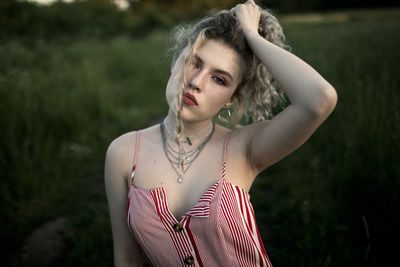 Portrait of young woman with hand in hair sitting on land