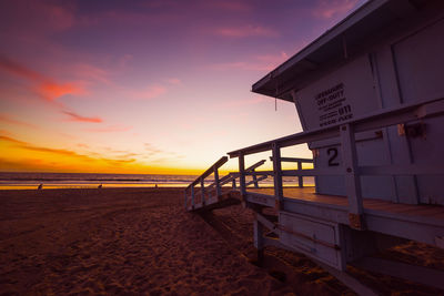 Lifeguard hut on beach against sky during sunset