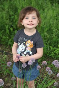 Portrait of cute girl standing on grassy field in park