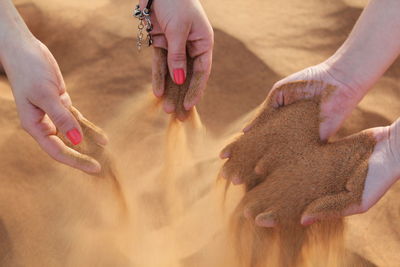 Women sifting sand through their fingers on the beach