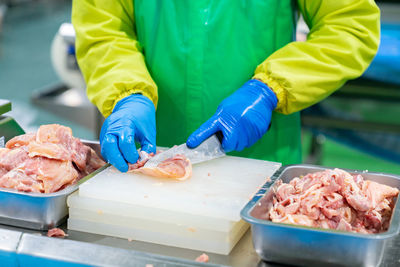 A worker cuts a piece of chicken in a production line slaughterhouse.