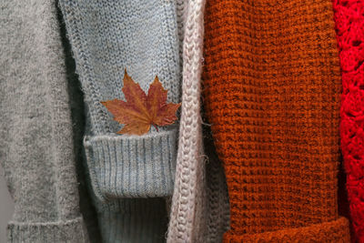 Stack of cozy knitted warm sweater with autumn fall maple leaf. sweaters in retro style. orange 