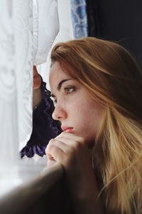 Side view of thoughtful teenage girl looking at window