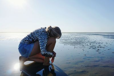 Side view of woman standing against sea