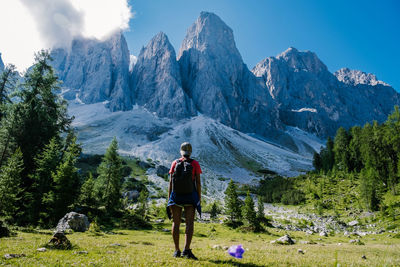 Rear view of man standing on mountain against sky