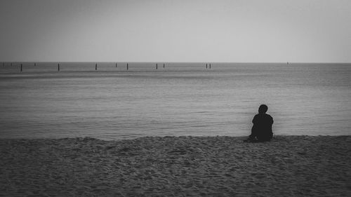 Rear view of man on beach against clear sky