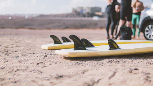 Close-up of surfing board against people standing at beach