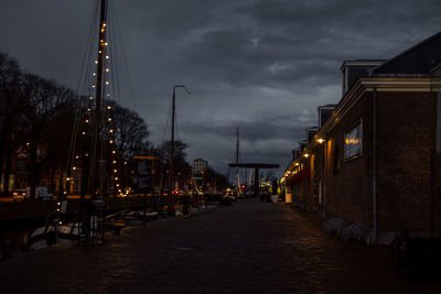 Illuminated street amidst buildings against sky at dusk