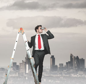 Full length of young man standing in front of skyscraper