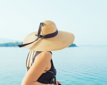 Rear view of woman in hat against sea