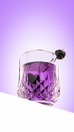 Close-up of purple flower in glass against white background