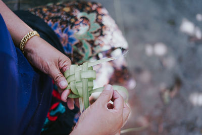 Midsection of woman weaving plants outdoors