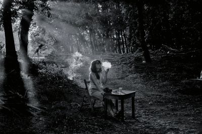 Woman sitting on seat in forest