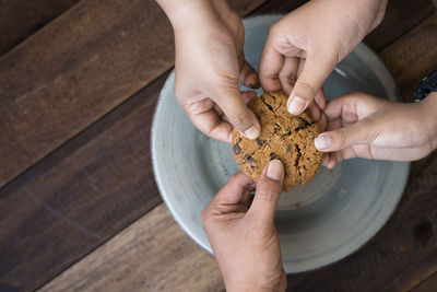 Close-up of hands holding cookie over plate