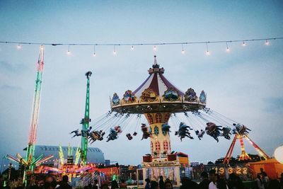 People at amusement park against sky