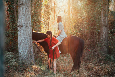 Rear view of women amidst trees in forest