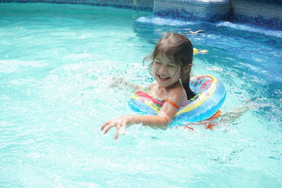 Little 5 year old girl playing with inflatables in the pool on her birthday