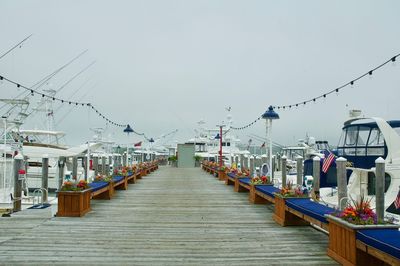 Wooden pier at harbor against sky