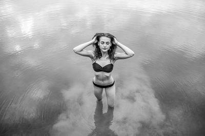 High angle view of young woman wearing bikini standing in lake