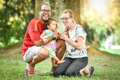 Full length of happy family on grassy field at park