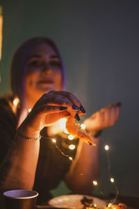 Portrait of woman holding illuminated string lights