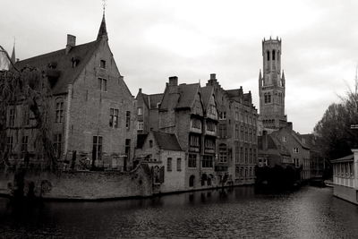 Buildings by river against sky