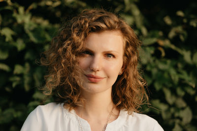 Portrait of young woman against plants