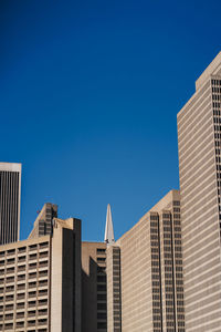 Low angle view of modern buildings against clear blue sky