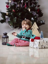 A little 12-month-old christmas elf with a christmas tree and gifts