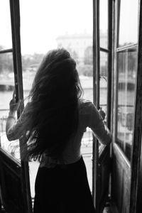 Rear view of woman looking through window