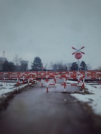 Road sign by trees against sky during winter