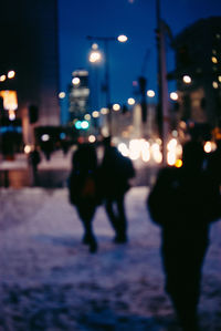 People walking on illuminated street at night