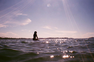 Silhouette woman paddleboarding on sea against sky