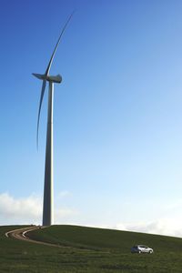 Windmill on field against blue sky