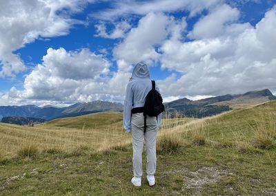 Rear view of man standing on mountain against sky