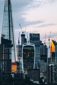 Modern buildings in city against sky during sunset