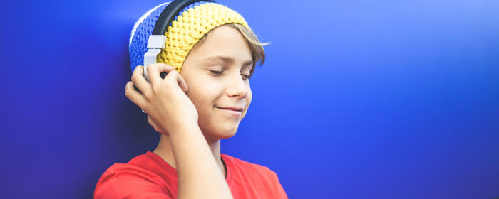Boy listening to music against blue background