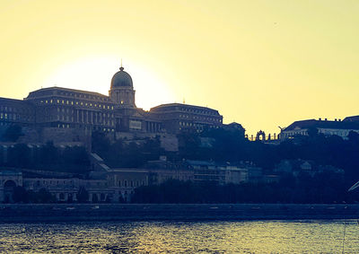 Buildings in front of river at sunset