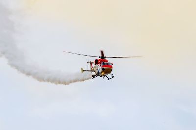 Low angle view of smoke emitting from helicopter against sky