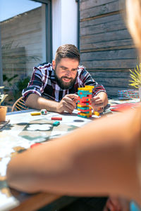 Bearded man catching jenga game piece with colleague on terrace