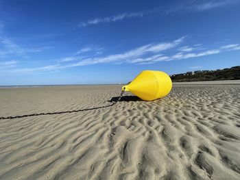 Yellow umbrella on beach against sky