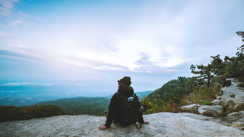 Rear view of woman standing on mountain against sky