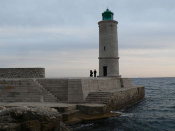 Lighthouse by sea against sky