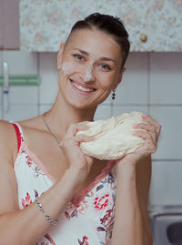 Girl smiles and holds dough for pie in her hands