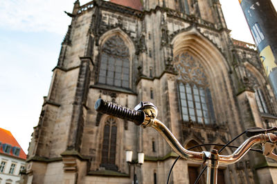 Low angle view of bicycle handlebar against historic building
